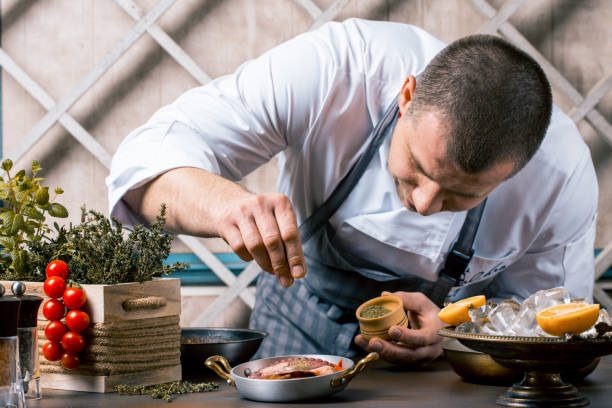 Chef sprinkling spices on dish from octopus in commercial kitchen. Gourmet Restaurant